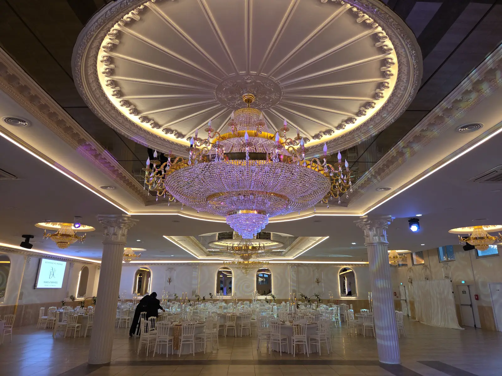 Le grand lustre en cristal sous la rosace dorée, la salle dressée